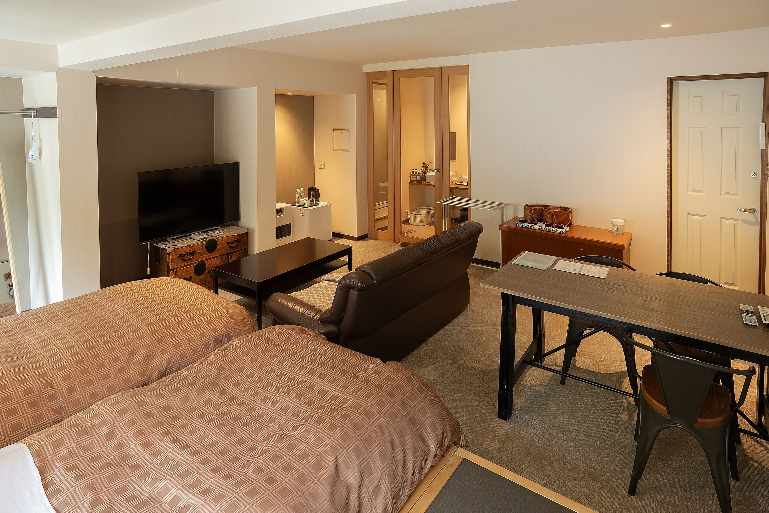 A hotel room with a bed, a TV, a desk, a chair, and a sofa.