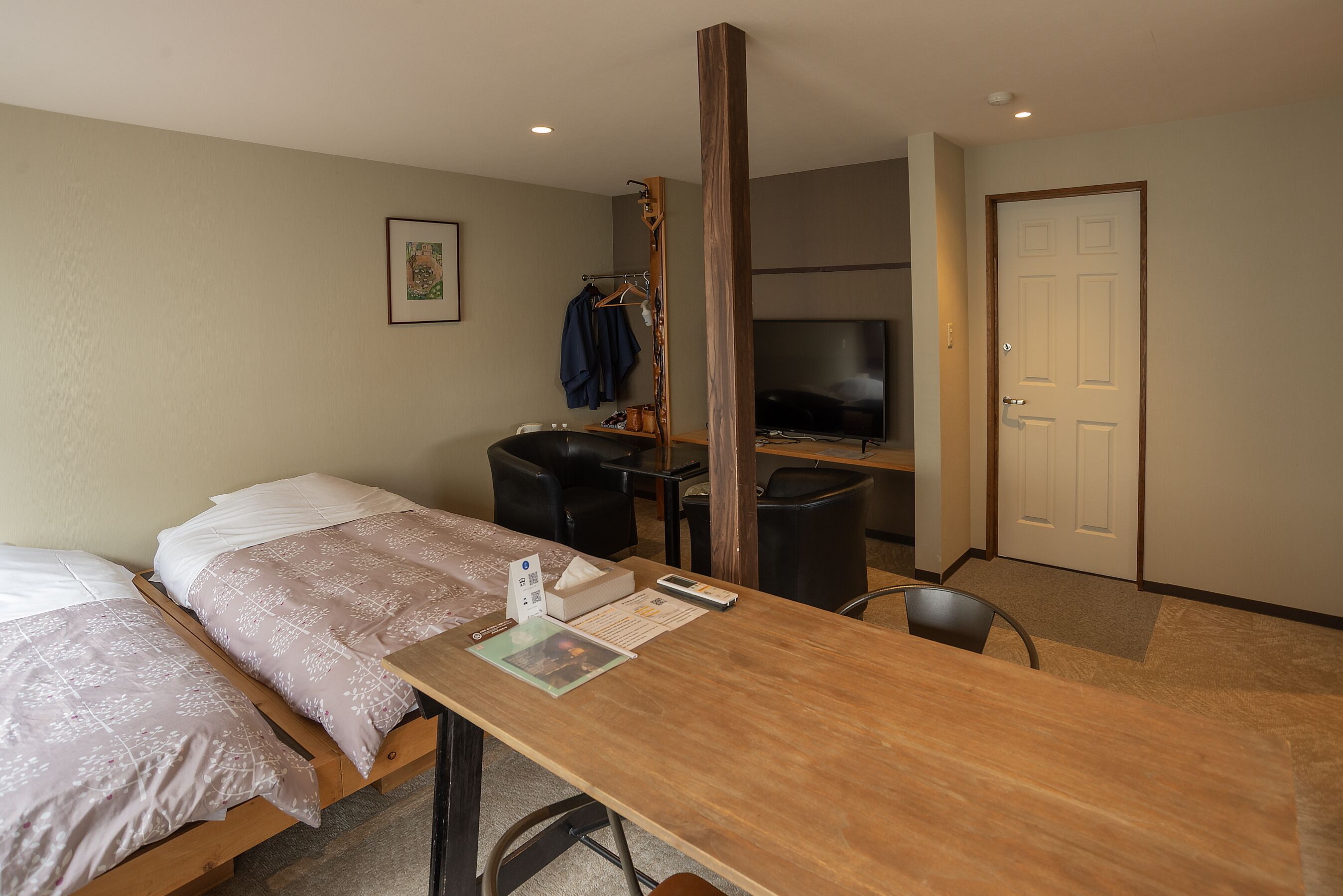 Una habitación de hotel con cama, escritorio, silla, televisor y puerta.