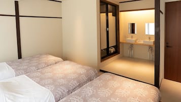 A bedroom with two beds, a bathroom with a mirror, and a wooden door.