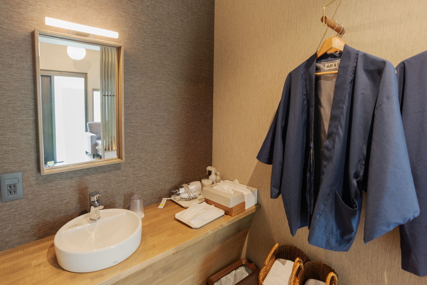 A bathroom with a large mirror, a sink, and a robe hanging on a rack.