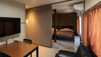Ein gemütliches Hotelzimmer mit Bett, Schreibtisch mit Stuhl, Fernseher und einer kleinen Küchenzeile.