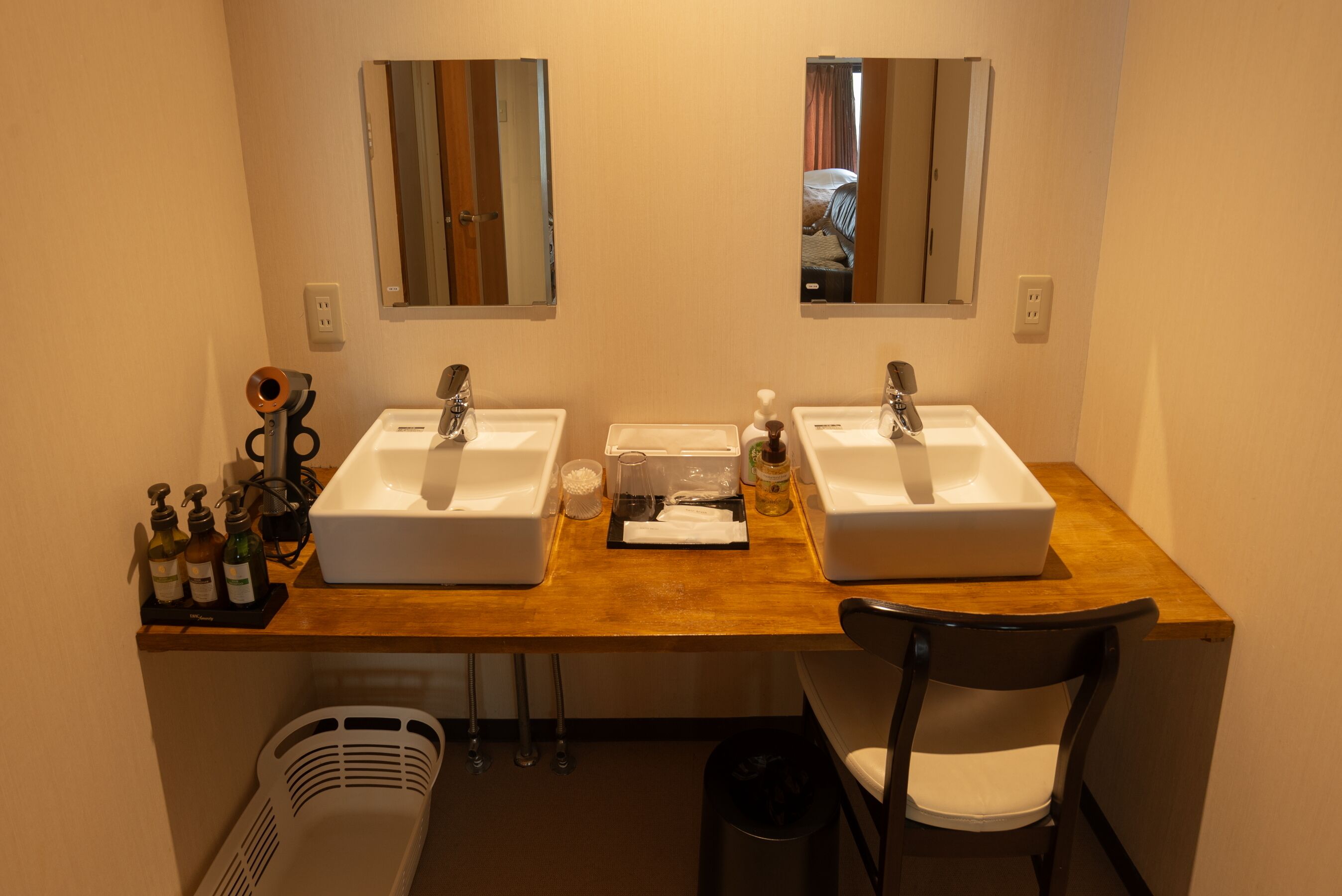 Un baño con dos lavamanos, un espejo, un perchero y una silla.