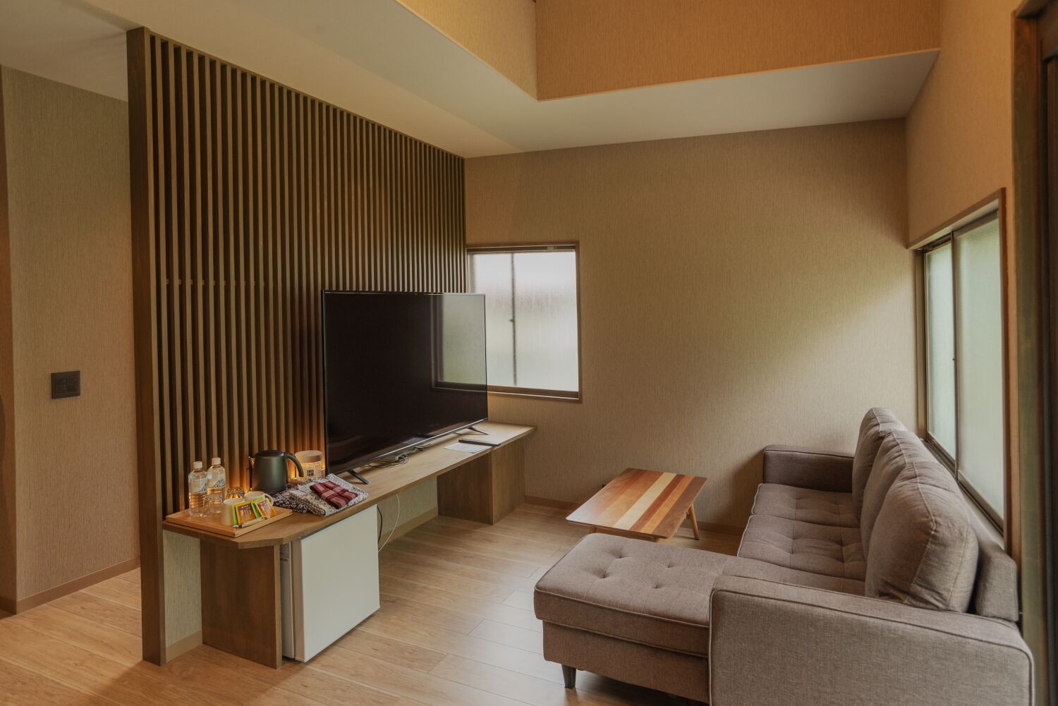 Uma sala de estar moderna com televisão de tela plana, um sofá, uma pequena mesa de madeira e um armário embutido.