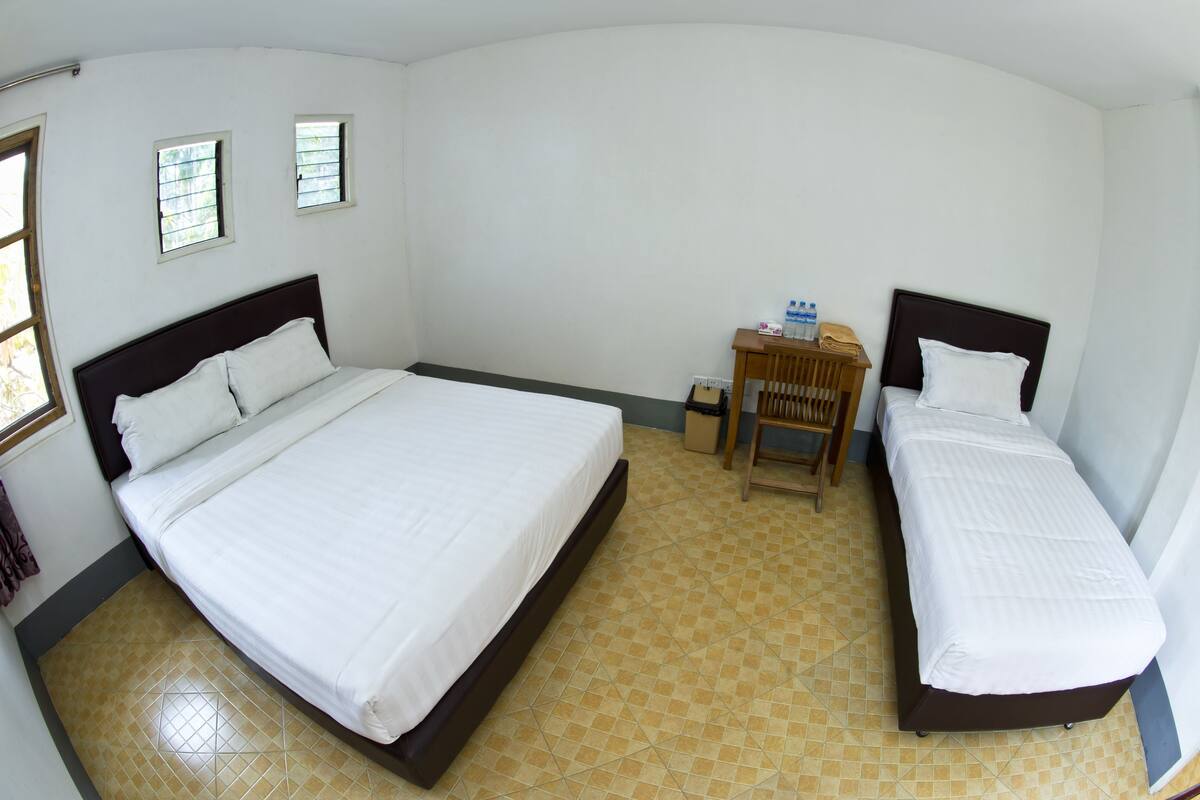Une chambre d’hôtel avec deux lits, un petit bureau avec une chaise et une fenêtre.