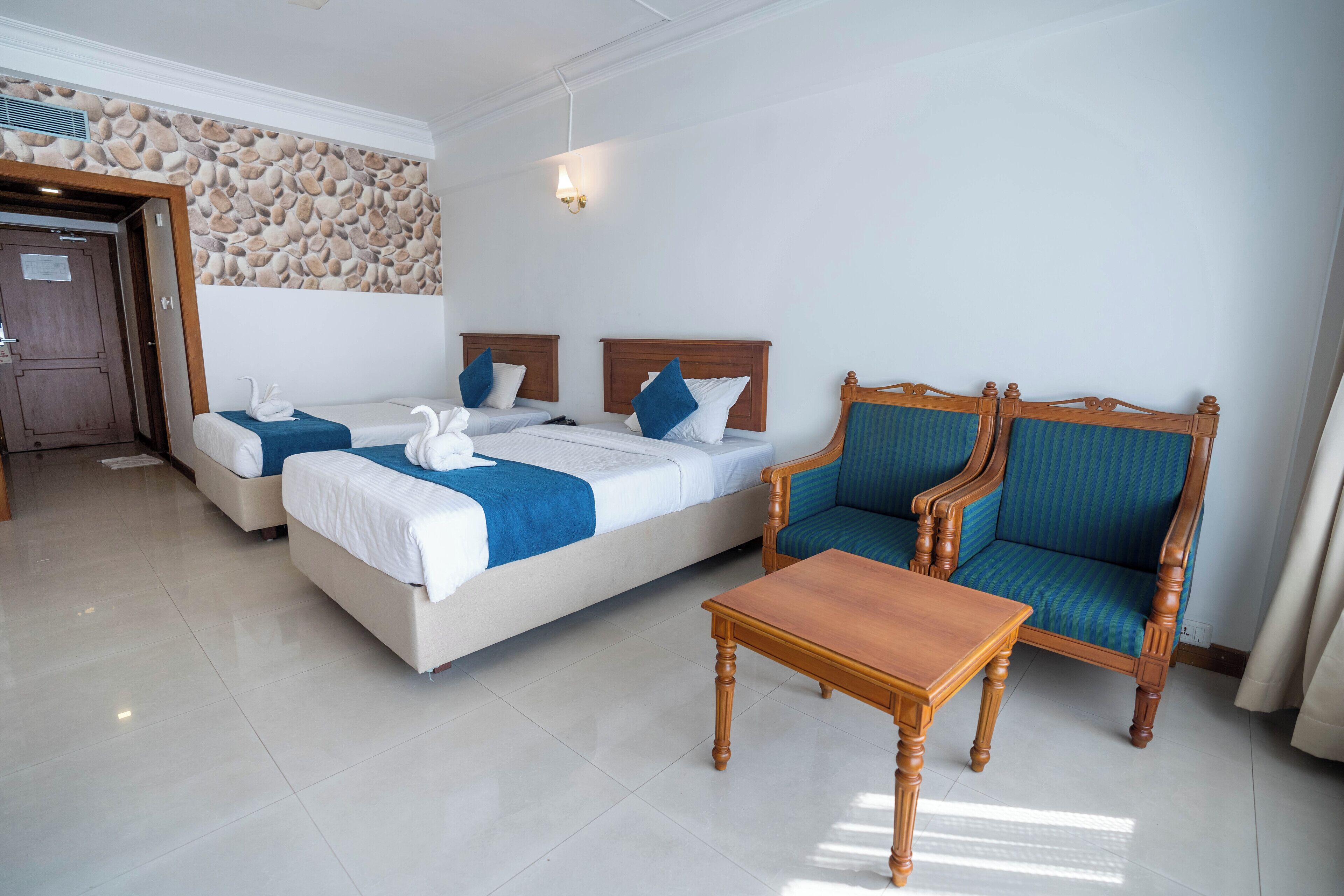 A hotel room with two beds, a wooden chair, and a small table.