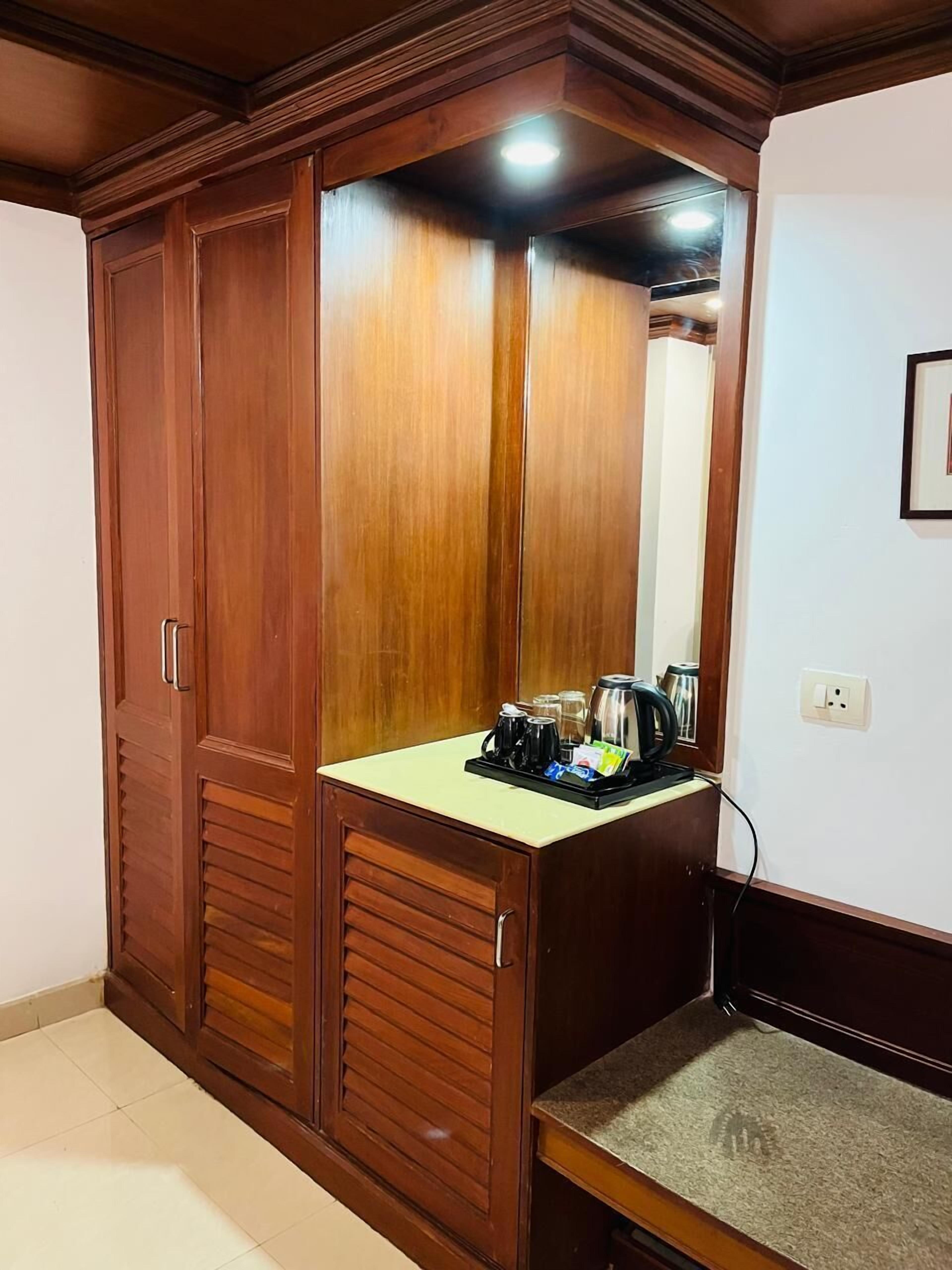 Un armario de madera con espejo y una encimera con artículos para preparar café.