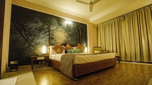 Ein Schlafzimmer mit einem großen Bett, einem Nachttisch, einem Sessel, einem Deckenventilator und einem Wandgemälde.