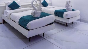 Ein modernes Hotelzimmer mit zwei Betten, weißen Wänden und Deckenleuchten.