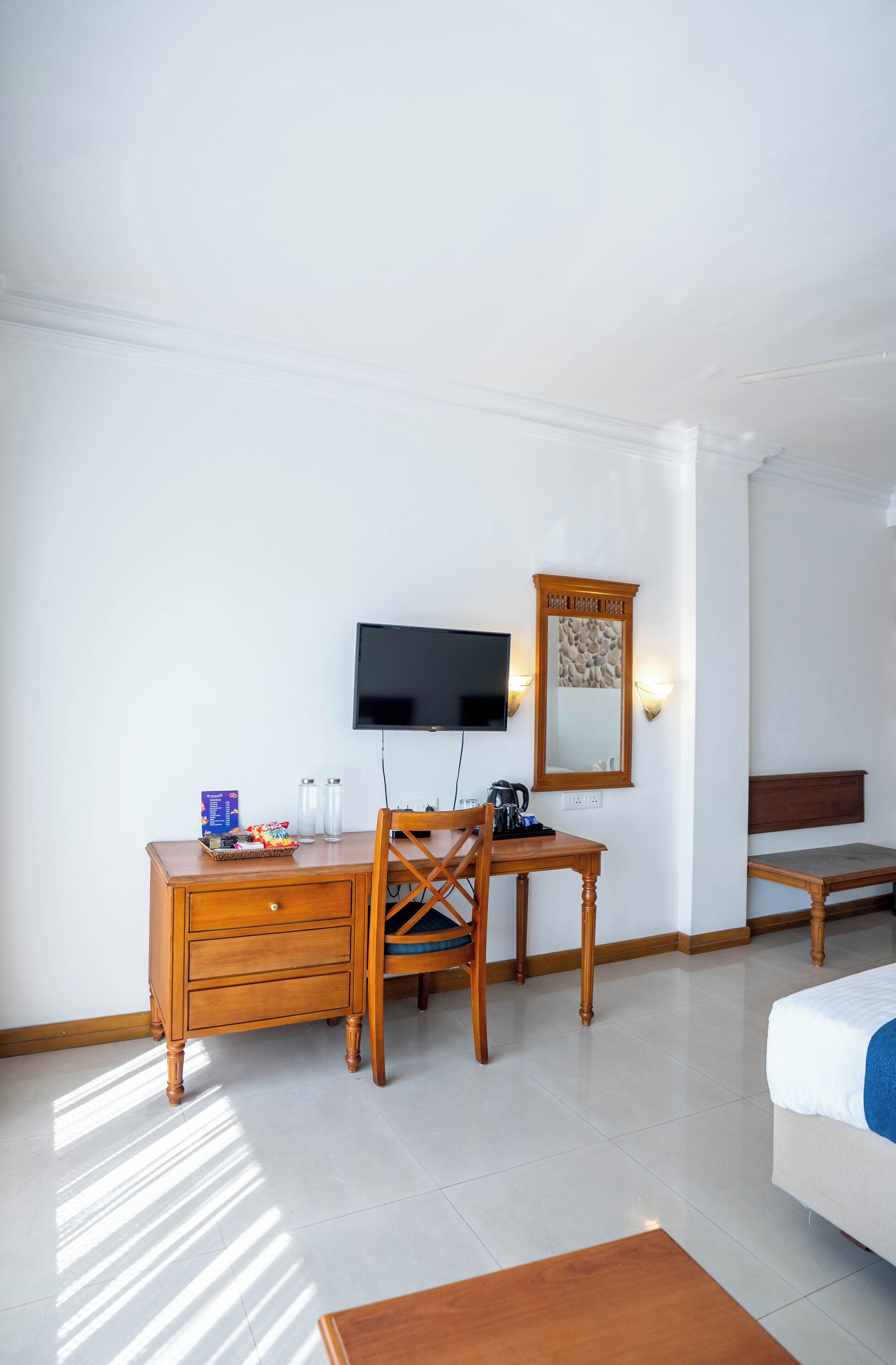 Een hotelkamer met een houten bureau, een televisie, een spiegel en een bed.