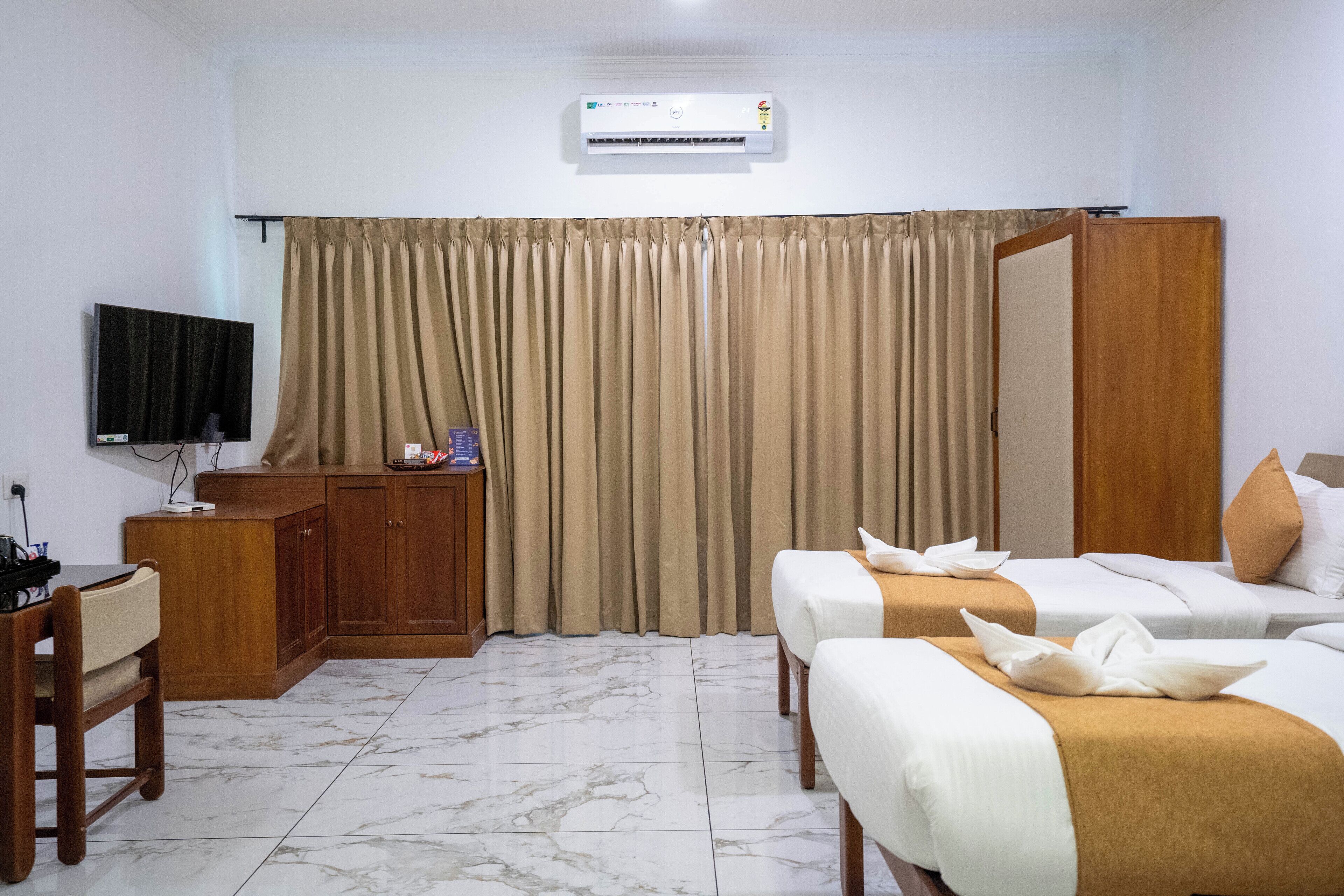 Una habitación de hotel con dos camas, televisión, escritorio y armario.