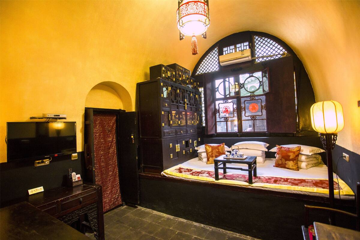 A traditional room with a bed, a television, a cabinet, and a lamp.