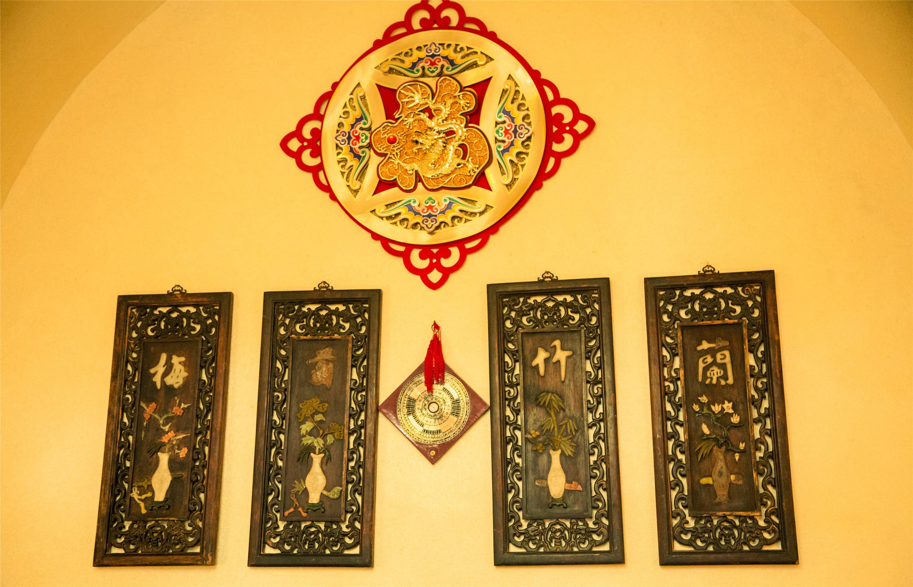 A wall with a decorative emblem and four framed artworks.