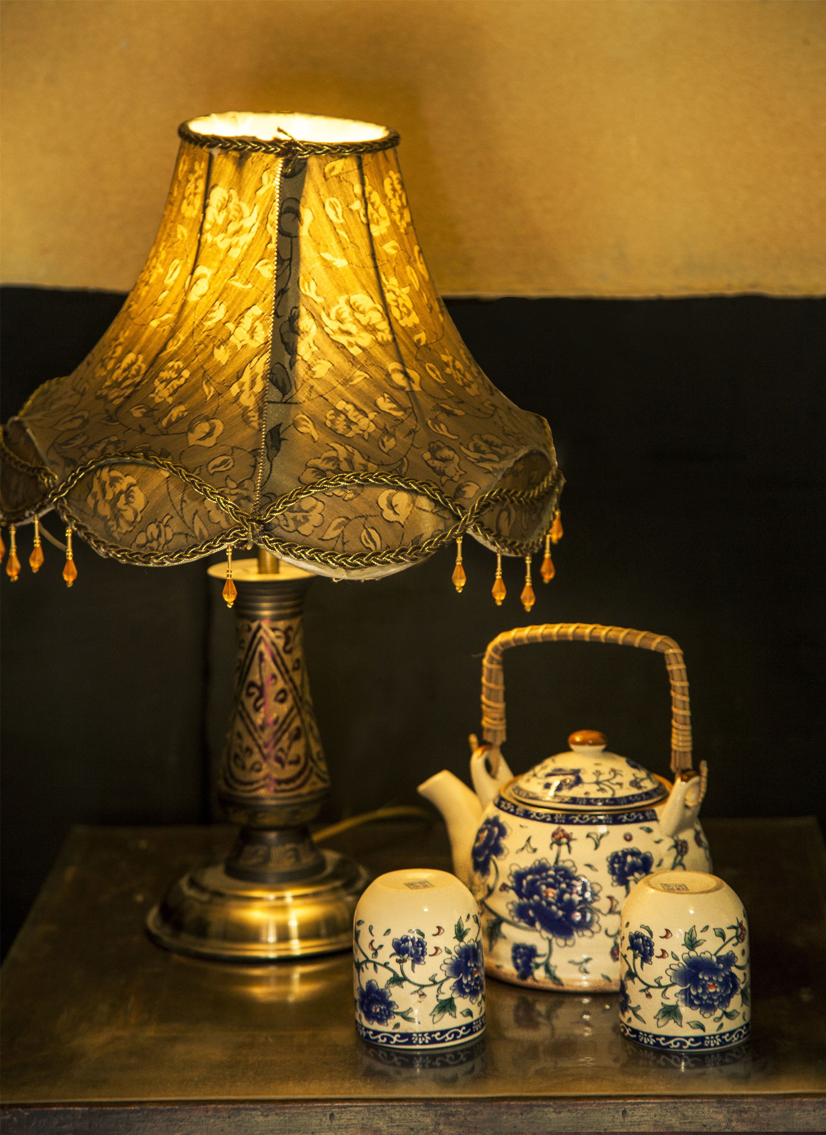 A table with a lamp, a teapot, and two cups.