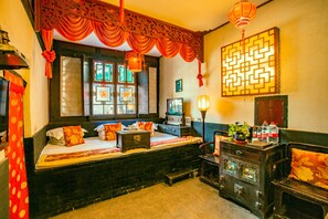 A traditional room with a bed, a wooden dresser, and a wall with decorative panels. - Pingyao Ji Family Courtyard Inn (Jinzhong)