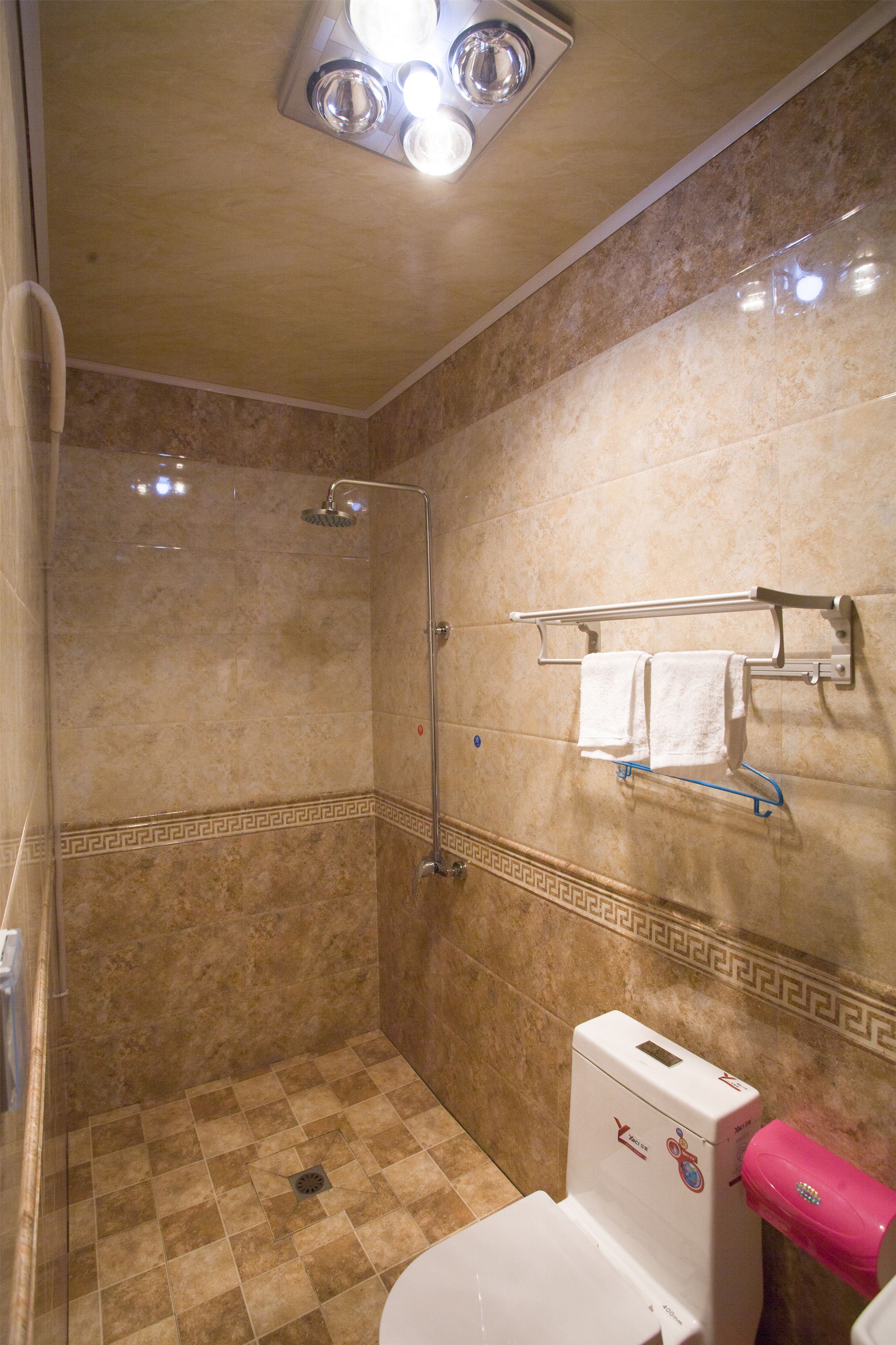 A bathroom with a shower, a toilet, and a towel rack.