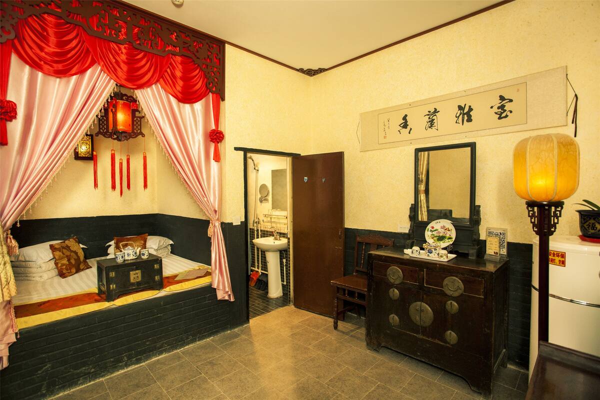 A traditional room with a bed, a dresser, a mirror, and a sink.