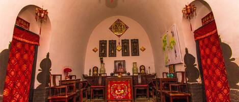 A traditional room with a central altar, wooden furniture, and red decorative elements.