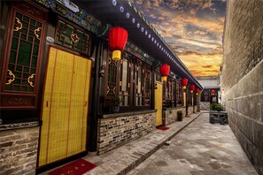 A traditional building with tiled windows, a wooden door, and red lanterns.