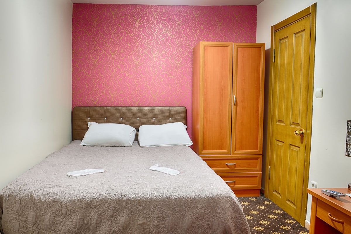 A hotel room with a bed, a wardrobe, and a desk.