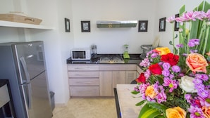 A modern kitchen with a refrigerator, microwave, and stove. There are wooden cabinets and a countertop. - Villa Vishuddha Ajna (Seminyak)