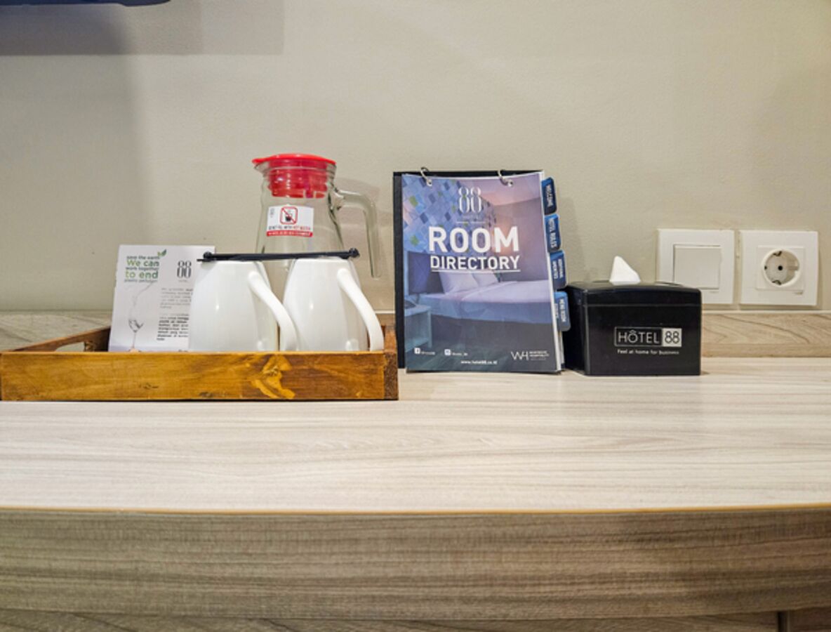 A hotel room counter with a room directory, a minibar, and a bottle of water.