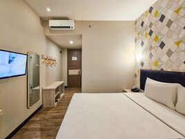 A hotel room with a bed, a TV, a desk, and a mirror.
