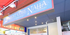 Une enseigne d’hôtel indiquant « Best Cube Naha » et « Kokusai Street », ce qui permet de situer l’établissement.