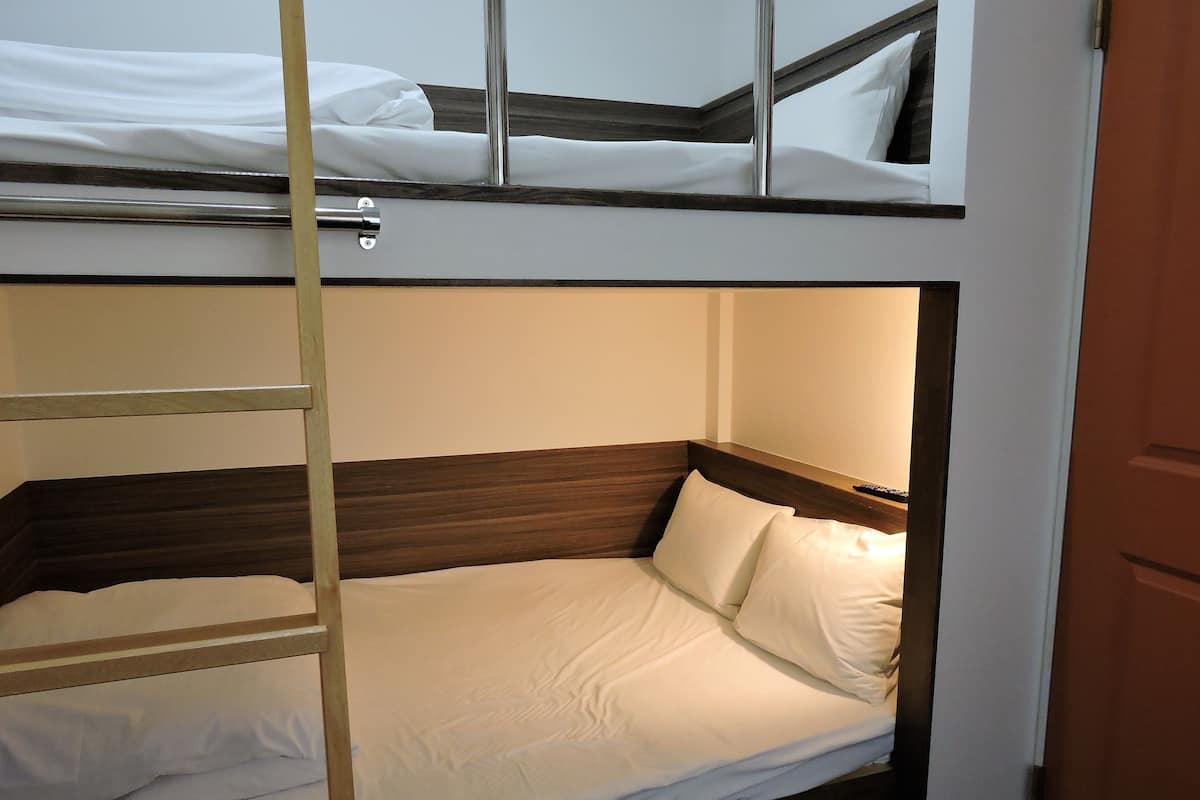 A bunk bed with a wooden headboard and white bedding.