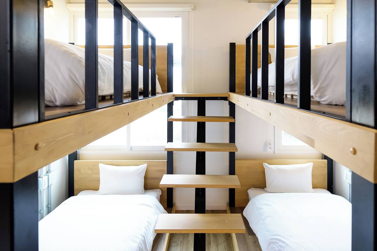 A dormitory-style room with bunk beds and a central staircase.