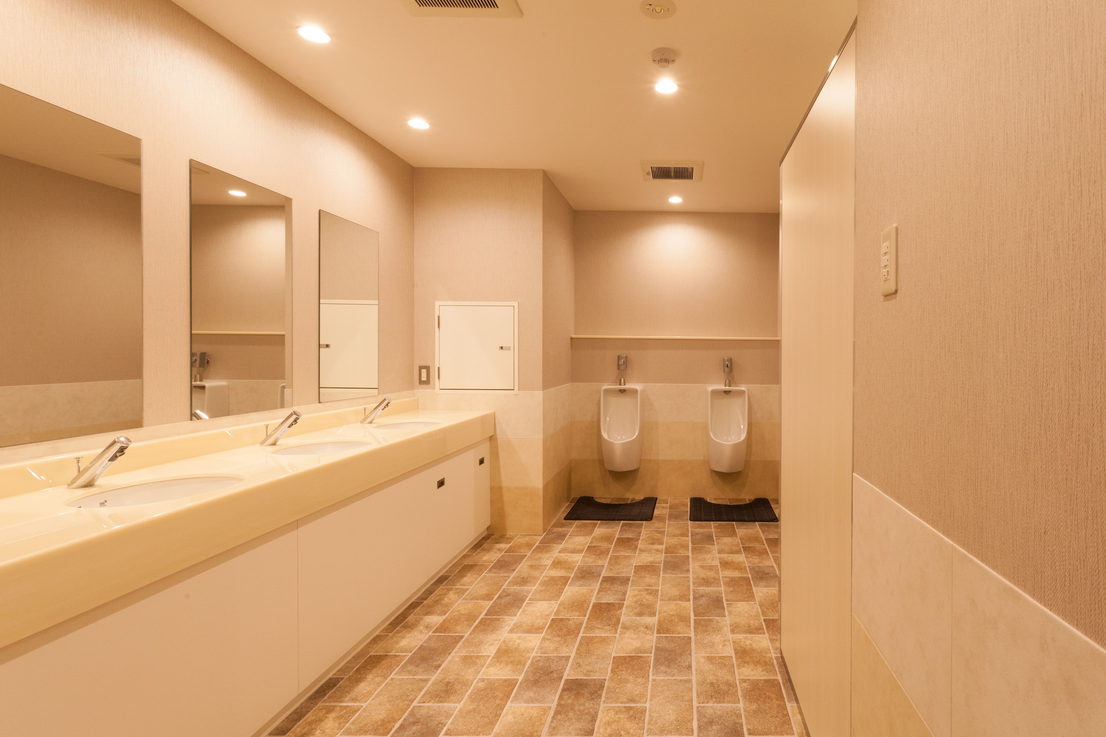 A public restroom with three sinks, urinals, and a mirror.