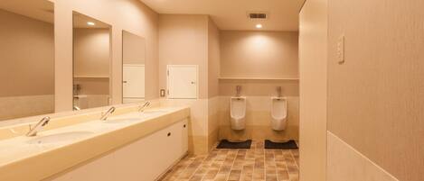 A public restroom with three sinks, urinals, and a mirror.