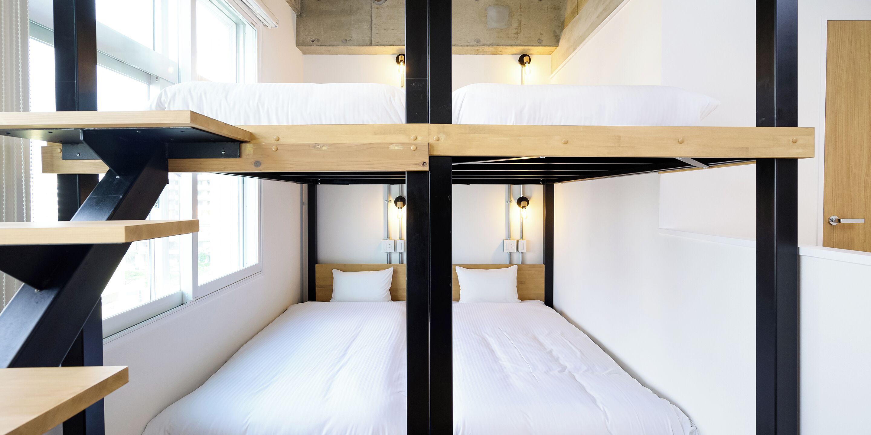 Habitación con literas de madera, ropa de cama blanca y dos lámparas de noche.