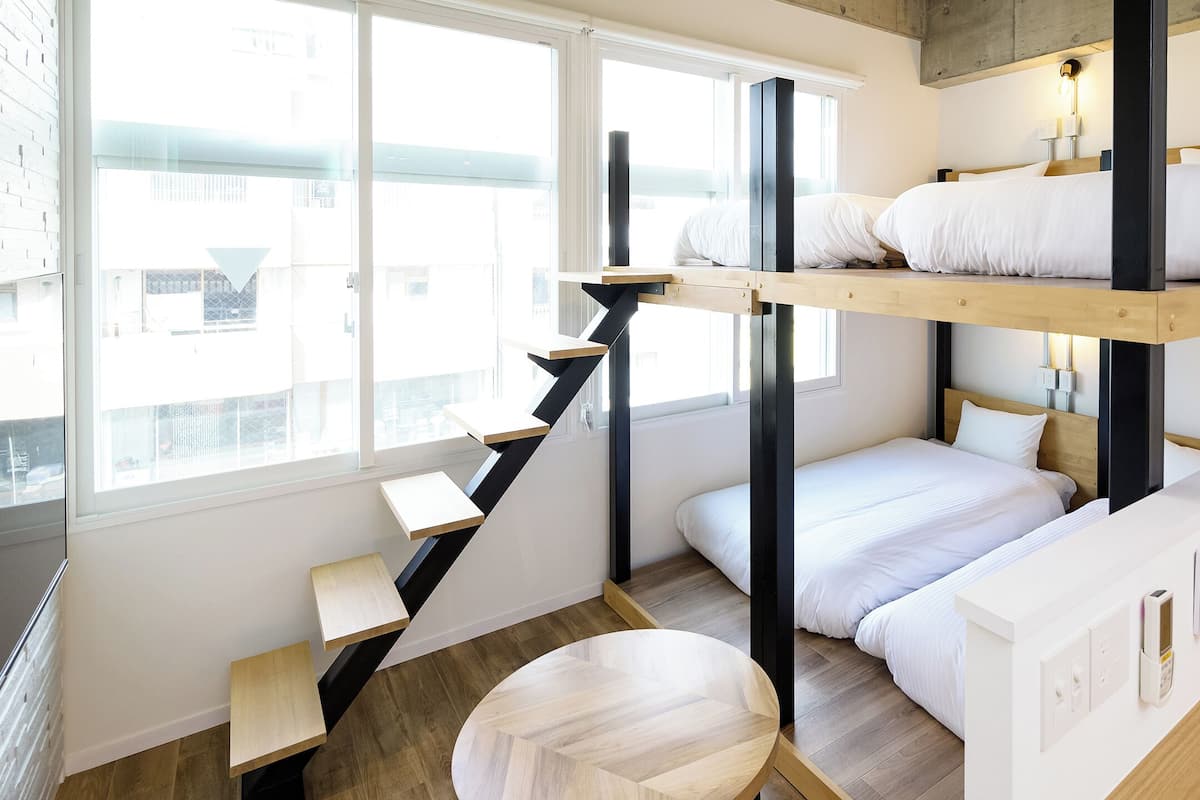 A compact, modern room with bunk beds, a small desk, and a staircase.
