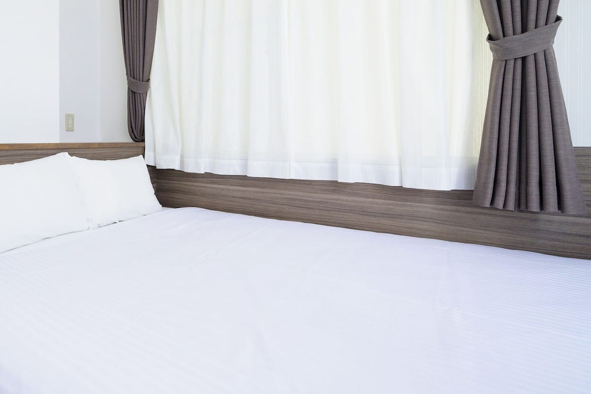A neatly made bed with white linens in a hotel room.