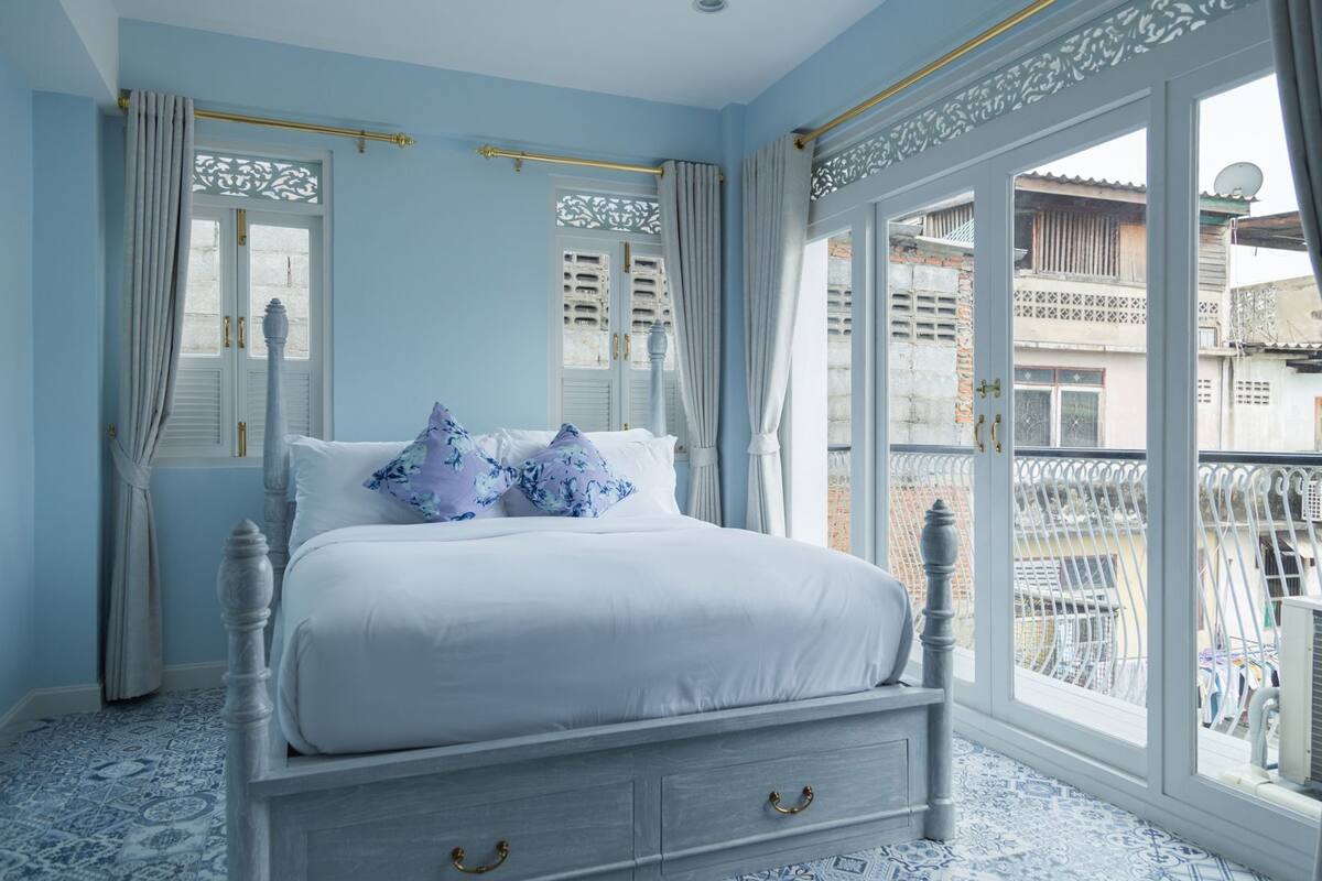 Une chambre à coucher avec un lit, des rideaux, une fenêtre et une vue sur le balcon.