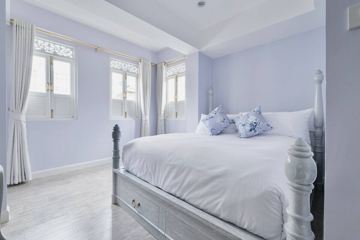 Une chambre à coucher avec un lit, des rideaux et une fenêtre avec des volets.