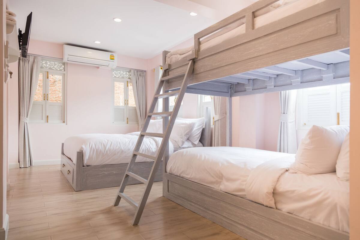 Une chambre avec deux lits, une échelle et un appareil de climatisation.