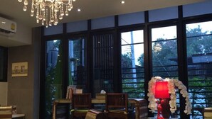 A hotel lobby with a chandelier, large windows, and checkered flooring. - Dino Studio (Kalasin)