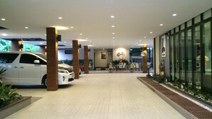 A modern hotel lobby with a tiled floor, a reception desk, and a seating area with chairs and tables. - Dino Studio (Kalasin)