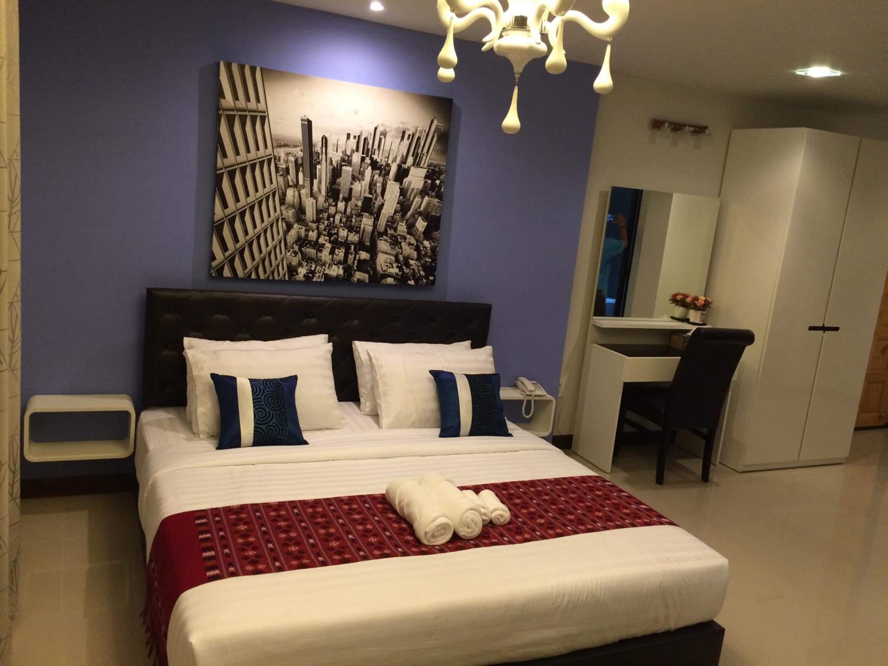 A hotel room with a large bed, a desk, and a chair.