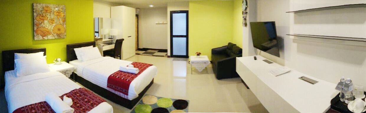 A hotel room with two beds, a desk, a TV, and a seating area.