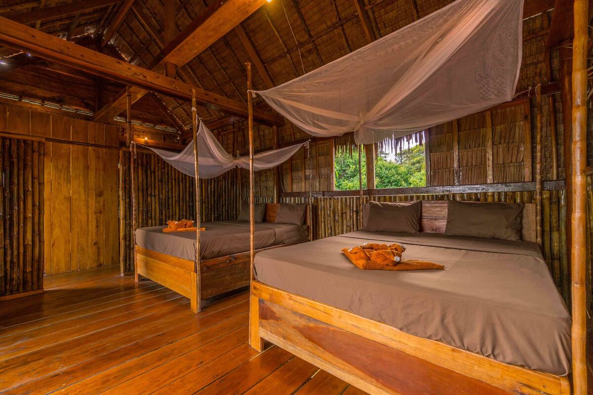 A wooden room with two beds, one with a canopy.