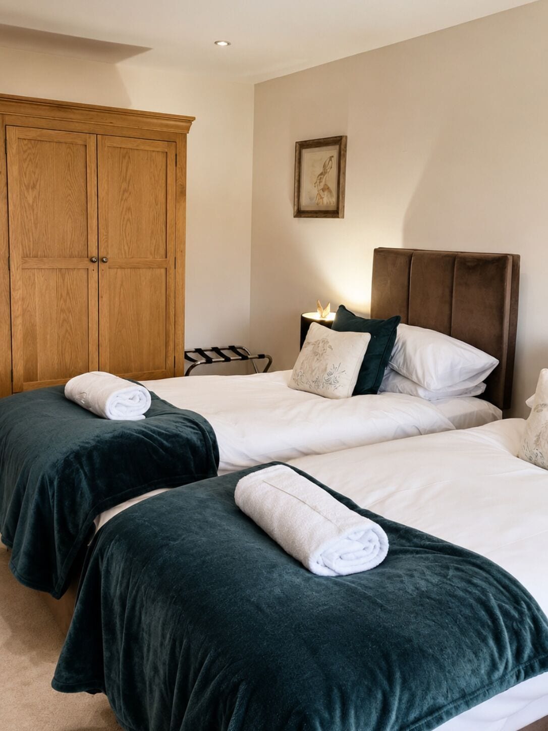 Ein Hotelzimmer mit zwei Betten, einem Holzschrank und einem gerahmten Bild an der Wand.