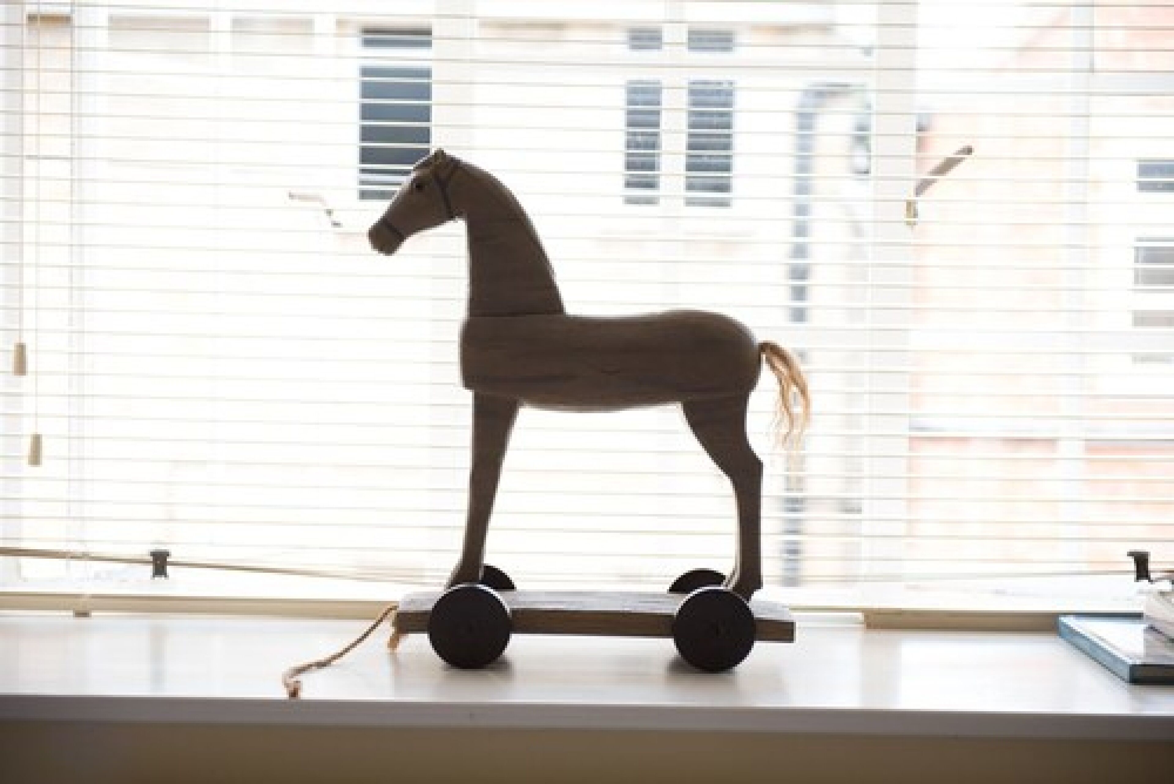 A wooden rocking horse on a windowsill.