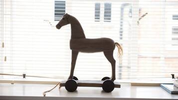 A wooden rocking horse on a windowsill.