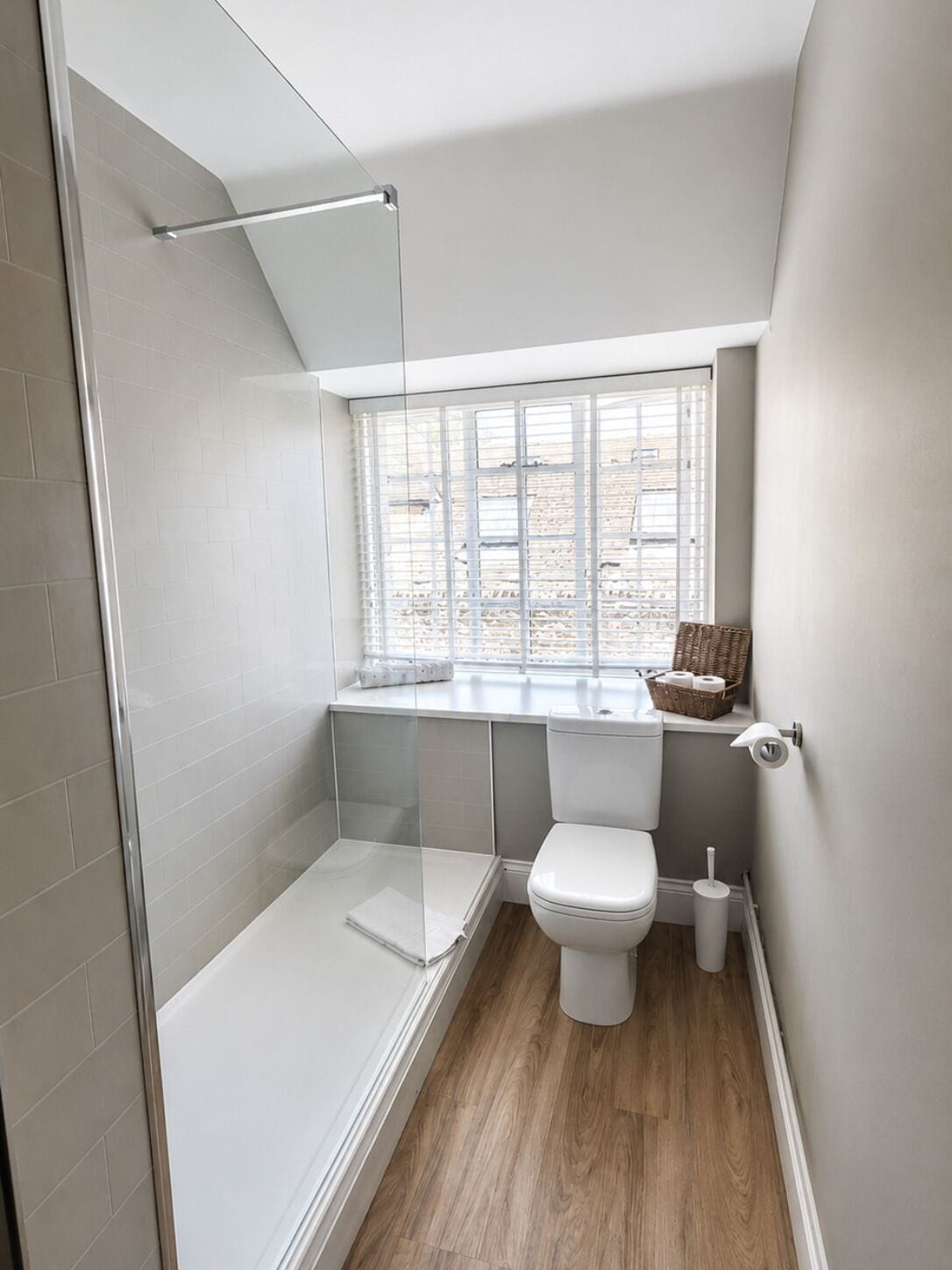 Un baño pequeño con ducha, inodoro y ventana.