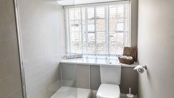 Un baño pequeño con ducha, inodoro y ventana.
