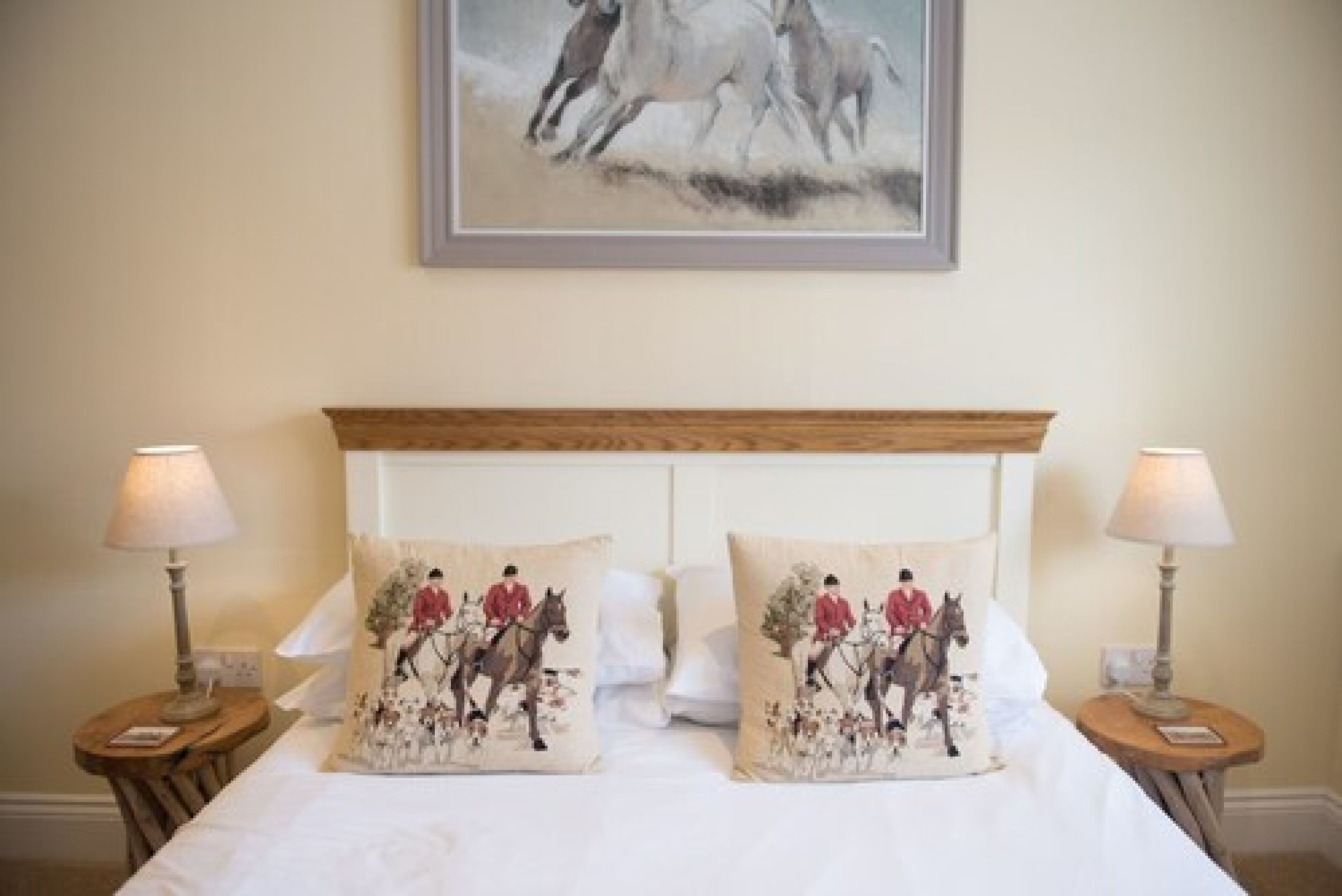 A bed with two matching pillows, a wooden headboard, and two bedside lamps.