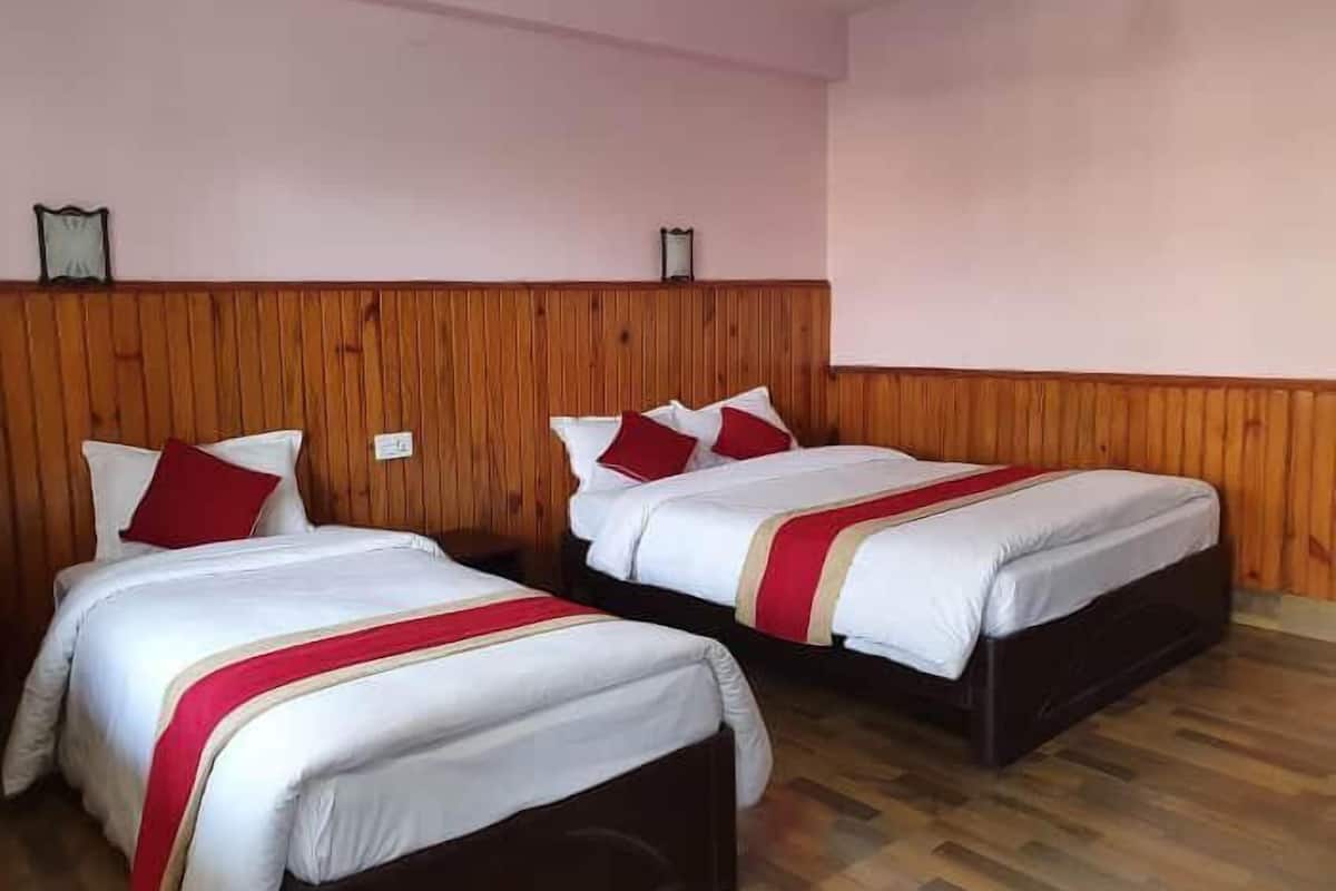 A hotel room with two beds, wooden headboard, and a wooden floor.