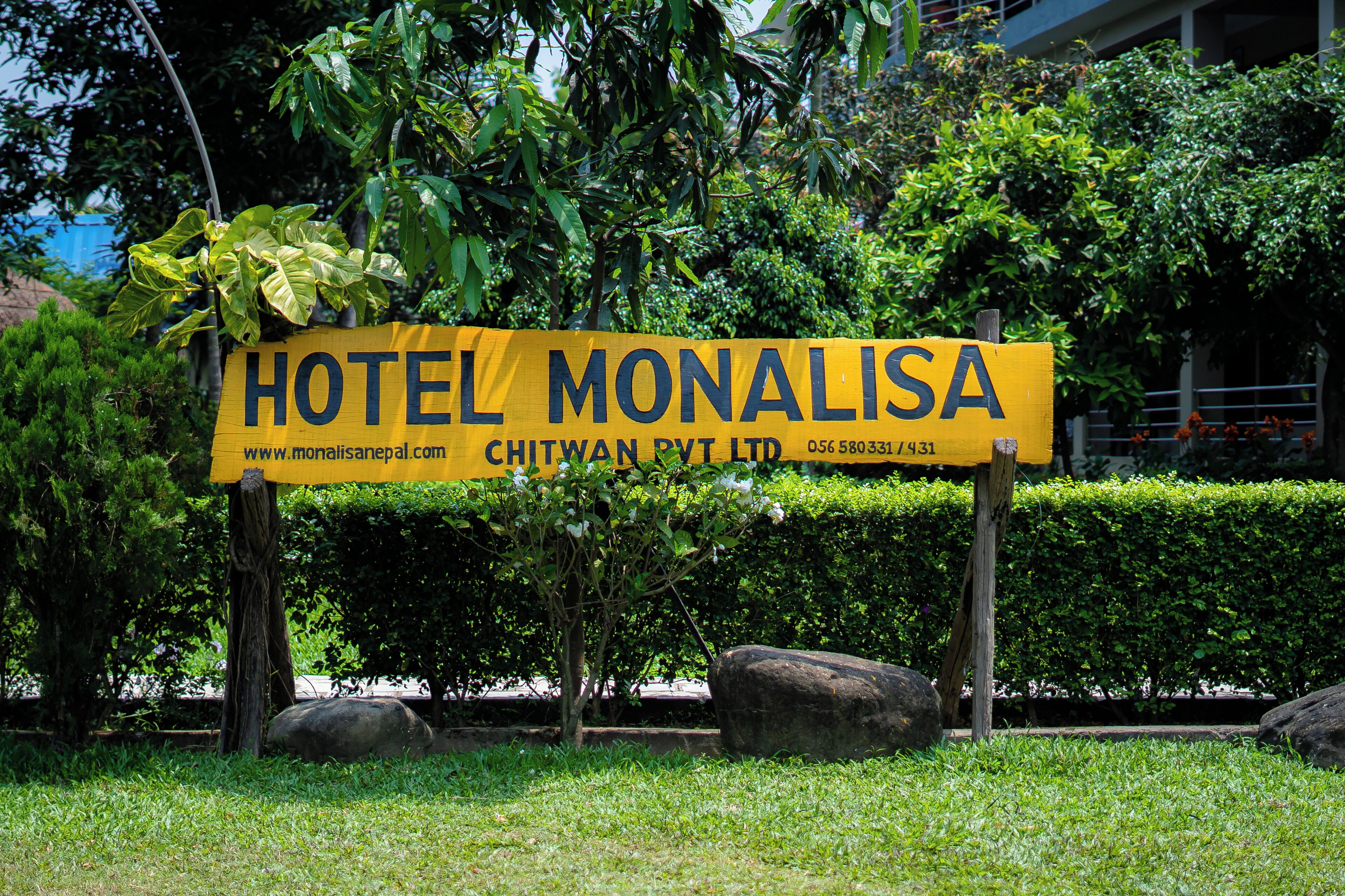 Un letrero amarillo del Hotel Monalisa con información de contacto y una dirección web.
